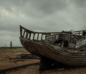 Abandoned boat on land against sky