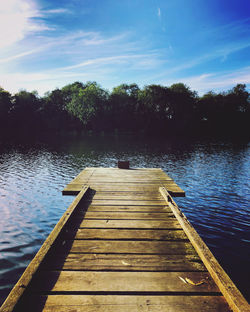 Wooden jetty on pier over lake against sky