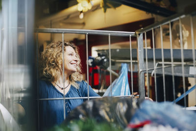 Smiling mature female volunteer by cart at warehouse