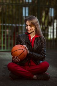 Young woman holding a ball on the basketball court.