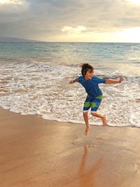 Full length of boy on beach against sky