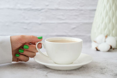 Midsection of woman holding coffee cup on table