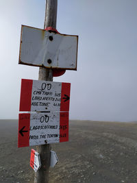 Information sign on field against sky
