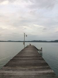 Pier over calm lake against sky
