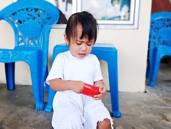 Full length of cute girl sitting against blue wall