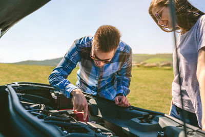 Young couple repairing car at beach