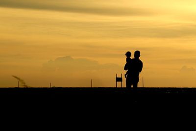 Silhouette man photographing against sky during sunset