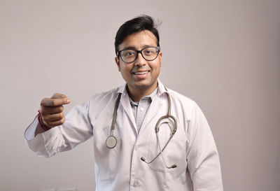 Portrait of smiling man standing against gray background