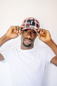 Young man adjusting cap against white background