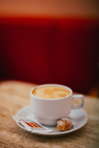 A cup of coffee and biscuit, against a red background of a cafe 