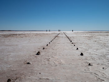 Path along salt lake in south australia, lake hart, with people silhouetted in the distance