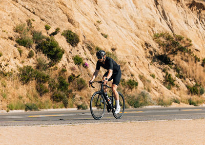 Rear view of man riding bicycle on road