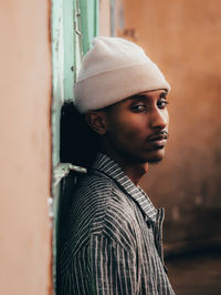 Portrait of young man standing by wall