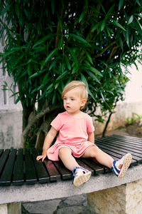 Full length of woman sitting against pink plants