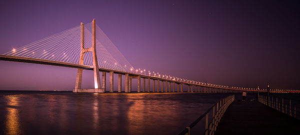 Low angle view of vasco da gama bridge over river against clear sky at dusk