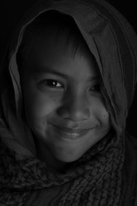 Portrait of boy smiling against black background