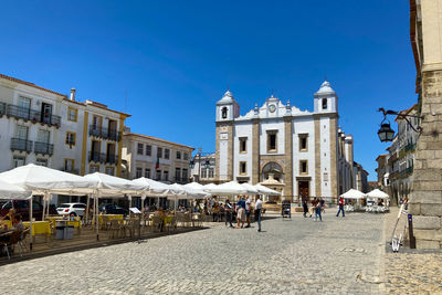 Group of people on street by buildings against sky in city