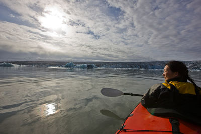 Woman rowing sea kayak on jökulsárlón glacier lagoon in iceland