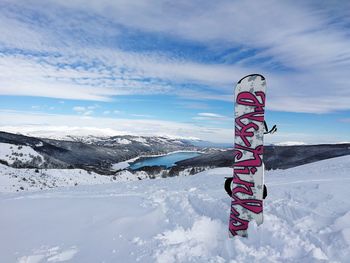 Information sign on snow covered landscape against sky