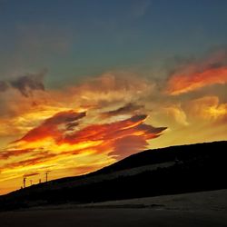 Silhouette landscape against dramatic sky during sunset