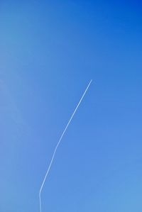 Low angle view of vapor trail against clear blue sky