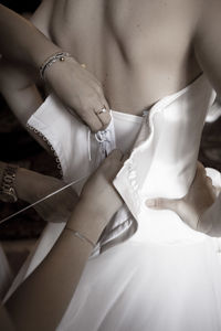 High angle view of woman hands helping to close a wedding dress 