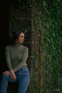 Portrait of young woman standing against wall