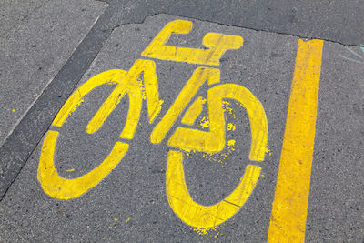 Close-up of yellow arrow symbol on road in city