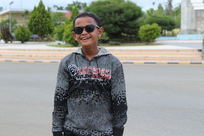 Portrait of young man wearing sunglasses while standing on road