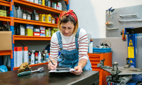 Woman checking stock in mechanic workshop