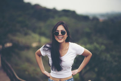 Portrait of smiling young woman standing against blurred background