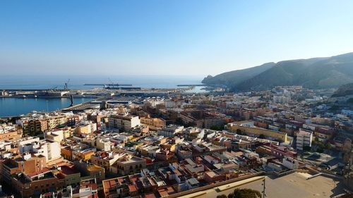 High angle view of townscape by sea against clear sky