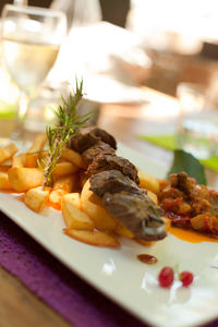 Close-up meat skewer with french fries and ratatouille on table