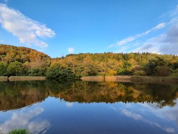 Scenic view of lake by trees against blue sky