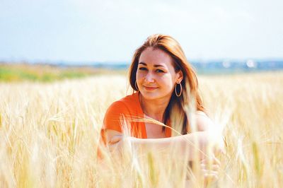 Portrait of smiling woman sitting on wheat field