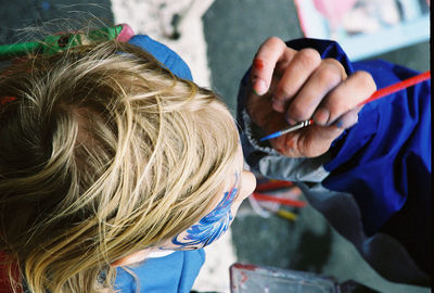 Cropped image of hand painting child face