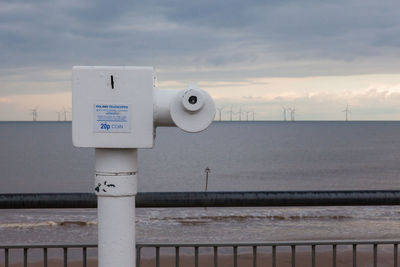 Information sign on sea against sky