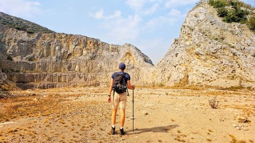 Full length rear view of man walking on mountain against sky