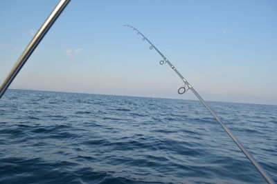 Close-up of fishing rod over sea against sky