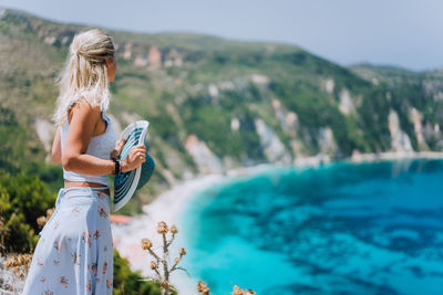 Woman standing on mountain by sea