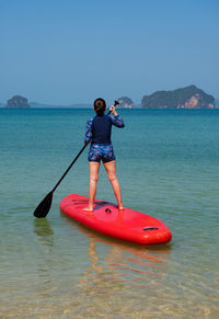 Young sporty woman playing stand-up paddle board on the blue sea in sunny day of summer vacation