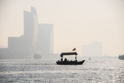 Boat sailing on sea against sky in city