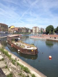 Boats moored on river in city against sky