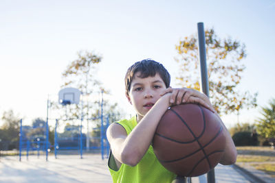 Portrait of boy playing with ball against sky