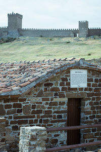 Old wall by building against sky