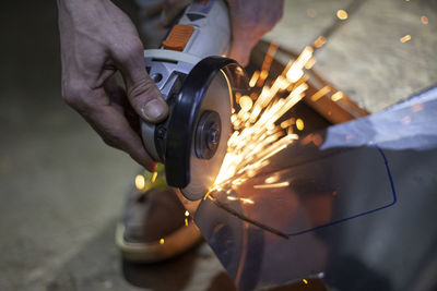 Cropped hands of person cutting glass with grinder