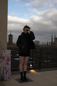 Side view of young woman standing against wall