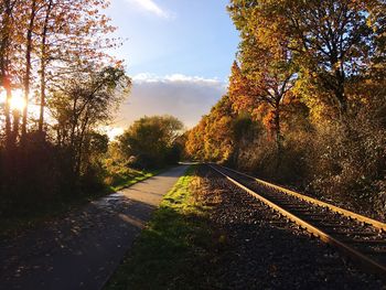 Railroad tracks amidst trees against sky during autumn