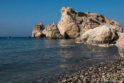 Rocks in sea against clear sky