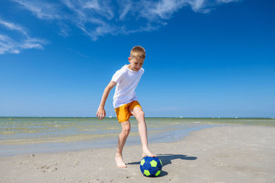 Full length of boy on beach against sky